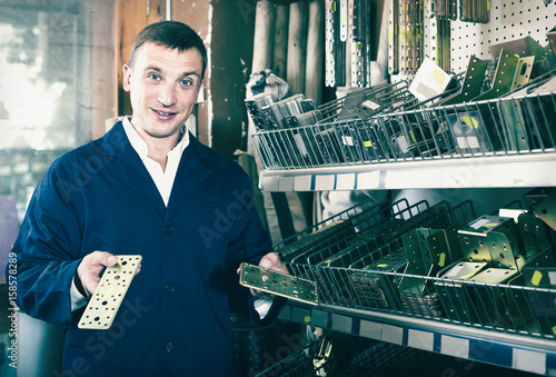 man seller wearing uniform having metal furniture in hands in store photo