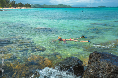 Woman snorkelling over coral reef in kailua beach, east shore in Oahu island, Hawaii, USA. Female bikini snorkeler swims in tropical sea. Watersport activity in Hawaii. Tropical destination holidays.
