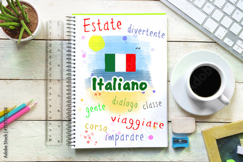Fototapeta Ręczne pisanie na zeszycie w klasie językowej z napisem „ITALIANO” - włoski - napisany dalej. Wręcza rysunek plażowa scena wewnątrz w lecie. Niektóre materiały w klasie.