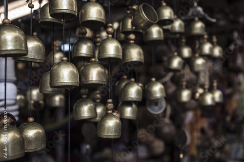 a lot of small brass brass bells hanging in the small souvenir shop in the asia - beautiful symbol of peace, harmony, balance, poise, goodness, compassion and meaningfulness