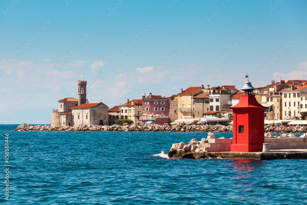 Cityscape of the old city Piran with historical medieval and new red lighthouses in summer.