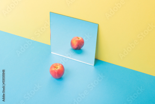 Apple on blue table isolated over yellow background near mirror
