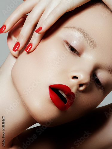 Beautiful woman with red matte lipstick. Beautiful woman face. Makeup detail. Beauty girl with perfect skin. Red lips and nails manicure