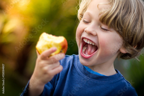 cute blonde child about to take a bite of an apple