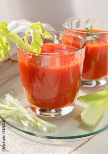 Two glasses of fresh tomato juice with thyme and celery.