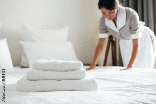 Young hotel maid setting up pillow on bed photo