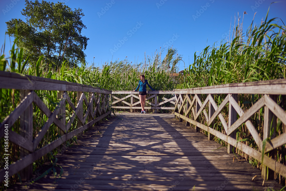Φωτογραφία Mujer joven apoyada en una pasarela de madera en la naturaleza