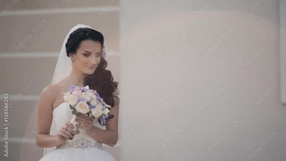 Beautiful brunette bride holding the bouquet. Woman in wedding dress smells the flowers. Female before wedding ceremony. Beautiful brunette bride holding the bouquet. Woman in wedding dress smells the flowers. Female before wedding ceremony.