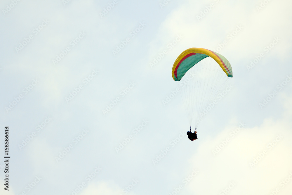 Paragliding over the mountains against clear blue sky Paragliding over the mountains against clear blue sky
