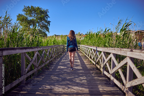 Mujer joven sobre una pasarela de madera Fototapet