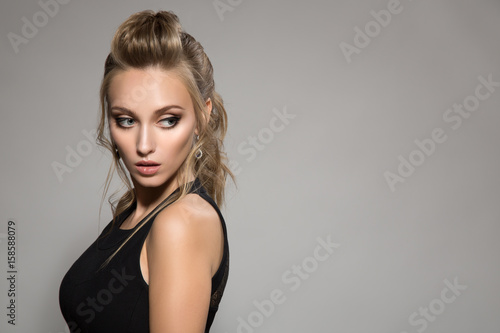 Beautiful woman in black dress. Hairstyle and bright make-up.