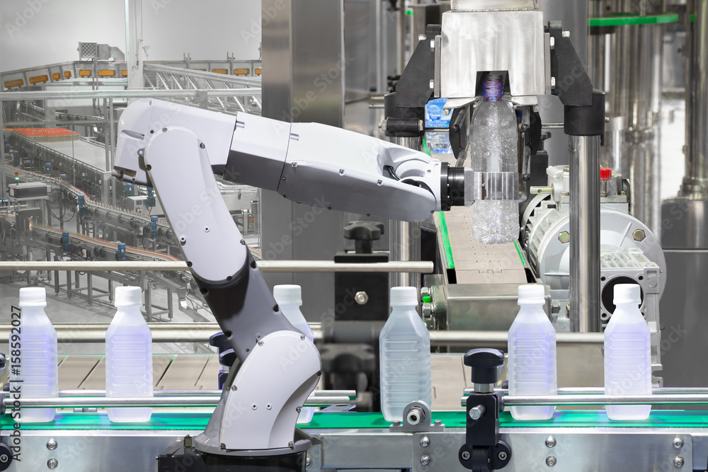 Robotic arm holding water bottles on drink production line in factory ...