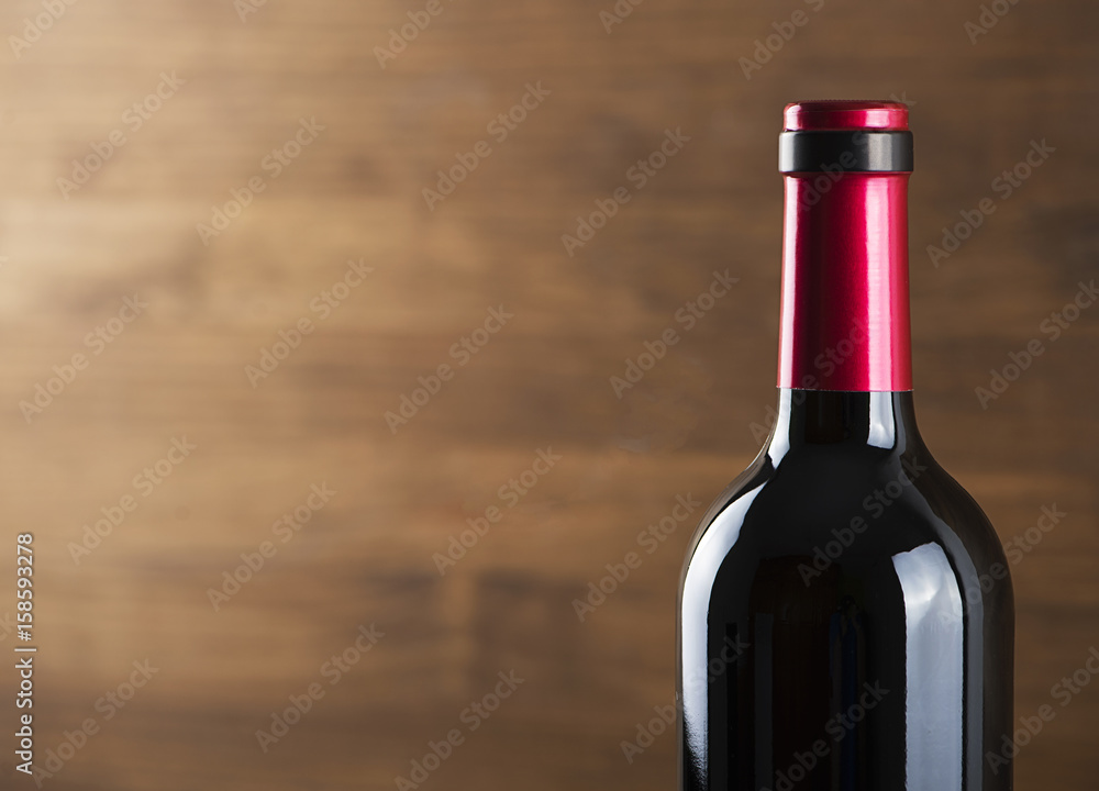 Close-up unlabeled red wine bottle placed on wooden table. Copy space. Horizontal studio shot Close-up unlabeled red wine bottle placed on wooden table. Copy space. Horizontal studio shot