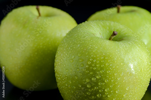 Green apples with droplets on black background