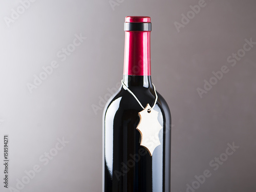 Close-up of red wine bottle with a sign around on gray background. Mockup. Vertica studiol shot. Drink photo