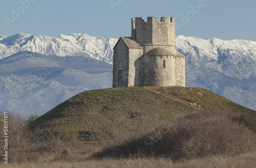 Church St. Nicholas near Nin on the prehistoric mound with snowy mountain Velebit in background, Croatia