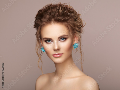 Fashion portrait of young beautiful woman with jewelry and elegant hairstyle. Beautiful model with curly hair. Perfect make-up. Beauty style model.