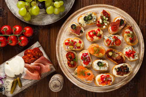 Crostini with different toppings on wooden background. Delicious appetizers. Top view.