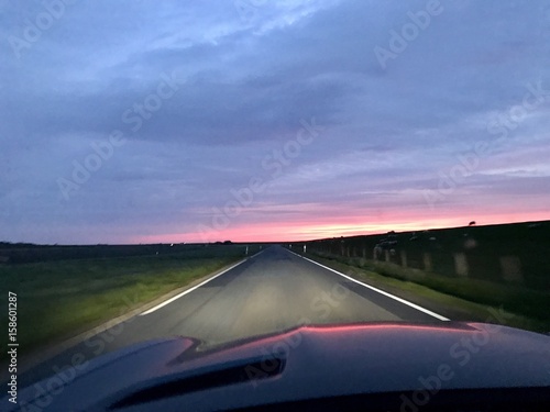 Bei Sonnenuntergang mit dem Auto auf der Landstraße unterwegs
