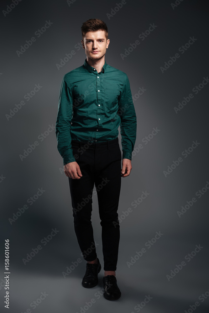 Handsome young man standing isolated over grey background