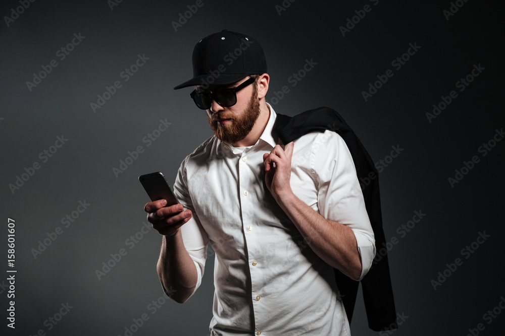 Man in sunglasses and shirt holding phone and looking away Man in sunglasses and shirt holding phone and looking away