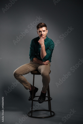 Concentrated young man sitting isolated over grey background © Drobot Dean