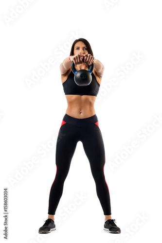 Sporty woman fitness model doing an exercise with weight on muscles of hands, legs set wide, hands in front of shoulder level on white isolated background © Виталий Сова