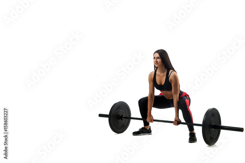 Young athletic woman doing deadlift with a barbell on a white isolated background, standing full squat