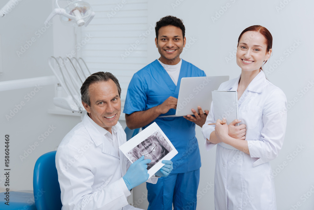Kind stomatologist showing different examples Kind stomatologist showing different examples