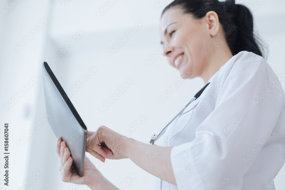 Cheerful therapist using tablet for work in the clinic Cheerful therapist using tablet for work in the clinic