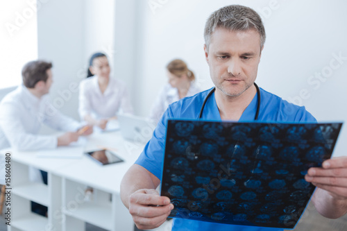 Bilde på lerret Serious neurologist examining mrt scan photo at the laboratory