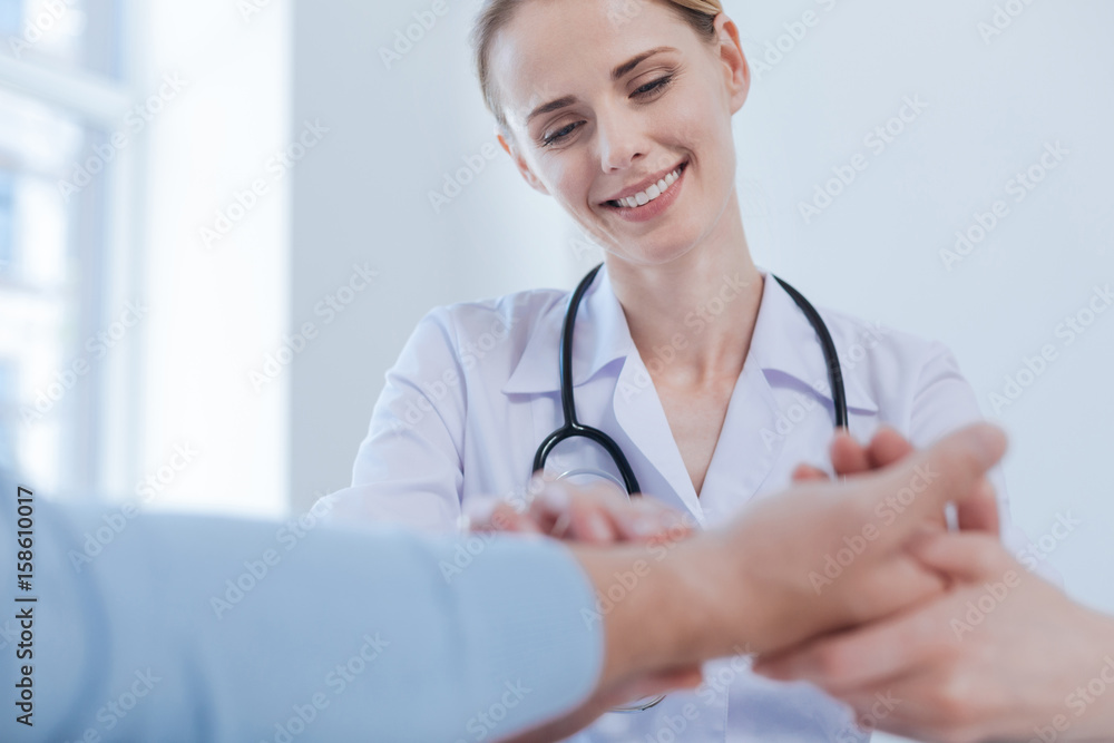 Experienced medic checking patient heart rate in the medical cabinet Experienced medic checking patient heart rate in the medical cabinet
