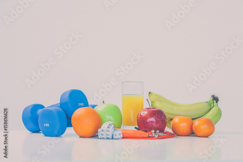 The concept of a healthy diet. Fintes meals. Sport lifestyle. Dumbbells. Oranges. Apples. Bananas. fruit juice. The skipping rope. Measuring tape waist. on a white background. studio shooting.