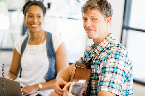 Students sitting on the floor with one playng guitar