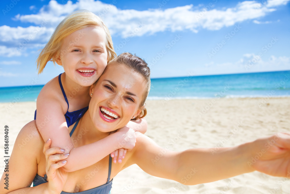 smiling young mother and child on seashore taking selfie smiling young mother and child on seashore taking selfie