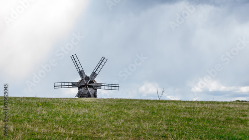 Ancient traditional wooden windmill, beautiful spring landscape with sky. National architecture. National Museum Pirogovo in the outdoors near Kiev.