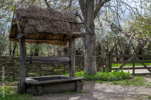 National Museum Pirogovo in the outdoors near Kiev. An ancient wooden well in the village against the backdrop of a spring landscape.