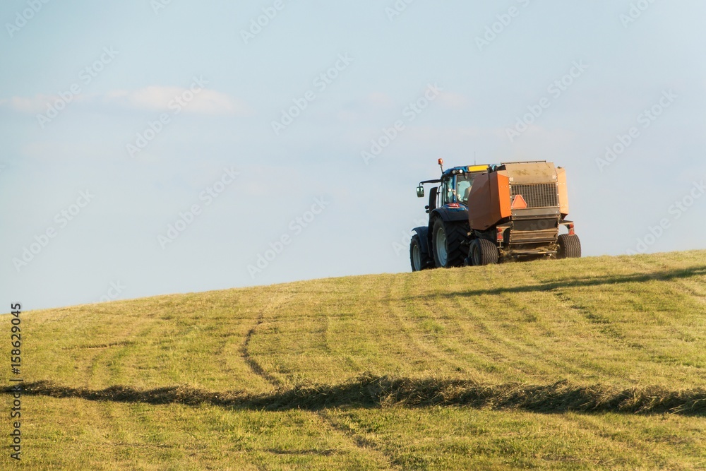 Fototapeta premium Blue tractor on the pasture.. Agricultural work on the farm in the Czech Republic.