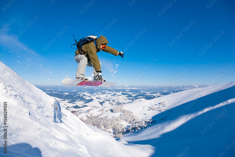 Beautiful sunny day in the mountains, winter, boarder jumping