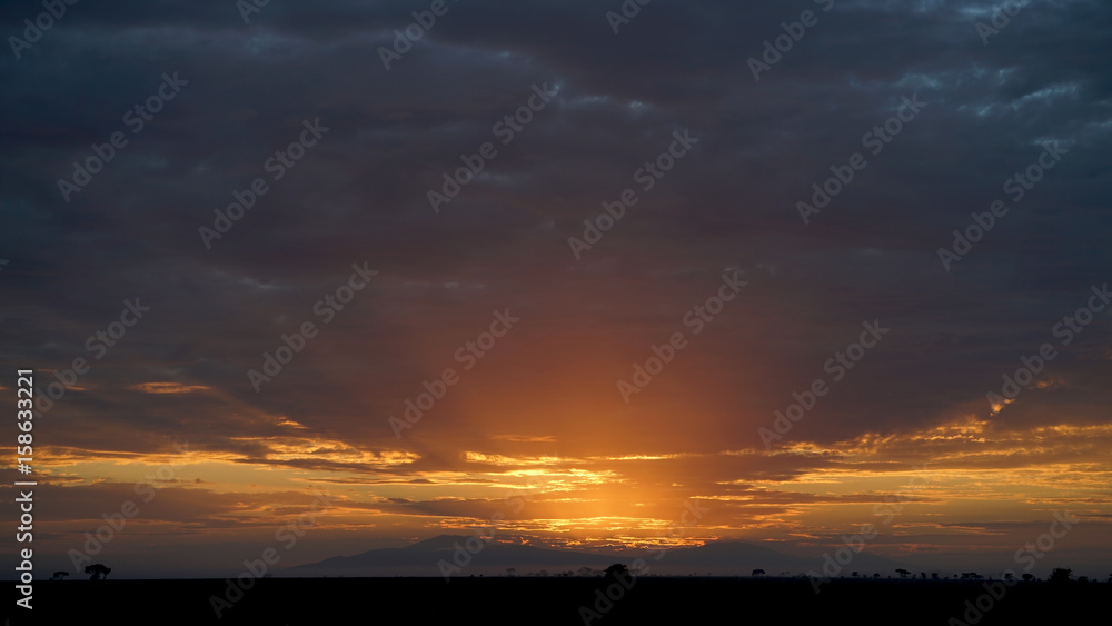 Sun rising through rain clouds in Serengeti, Tanzania