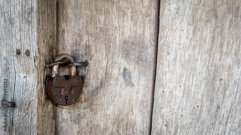 Natural material. Old metal rusty padlock, bolt on a wooden door. Old wooden brown background close-up. Natural material. Old metal rusty padlock, bolt on a wooden door. Old wooden brown background close-up.