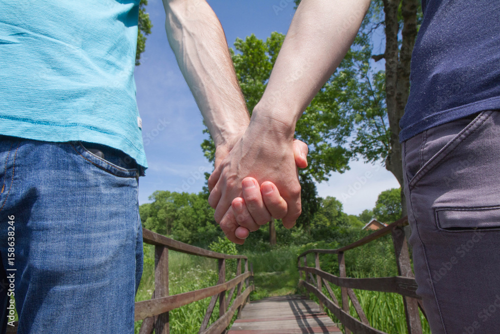 Man and woman holding hands with a wooden bridge in the background Man and woman holding hands with a wooden bridge in the background