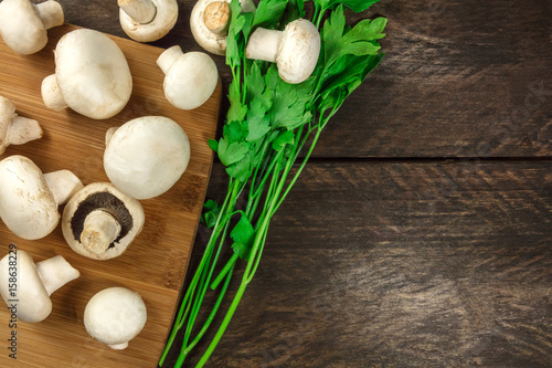 Overhead photo of white mushrooms with green parsley leaves