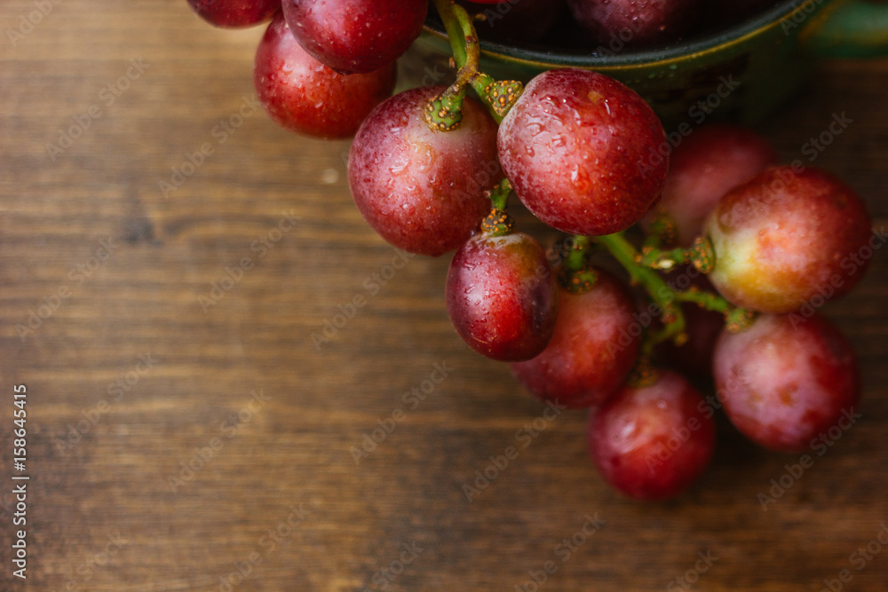 bunch of grapes on ceramic bowl over the wooden background bunch of grapes on ceramic bowl over the wooden background