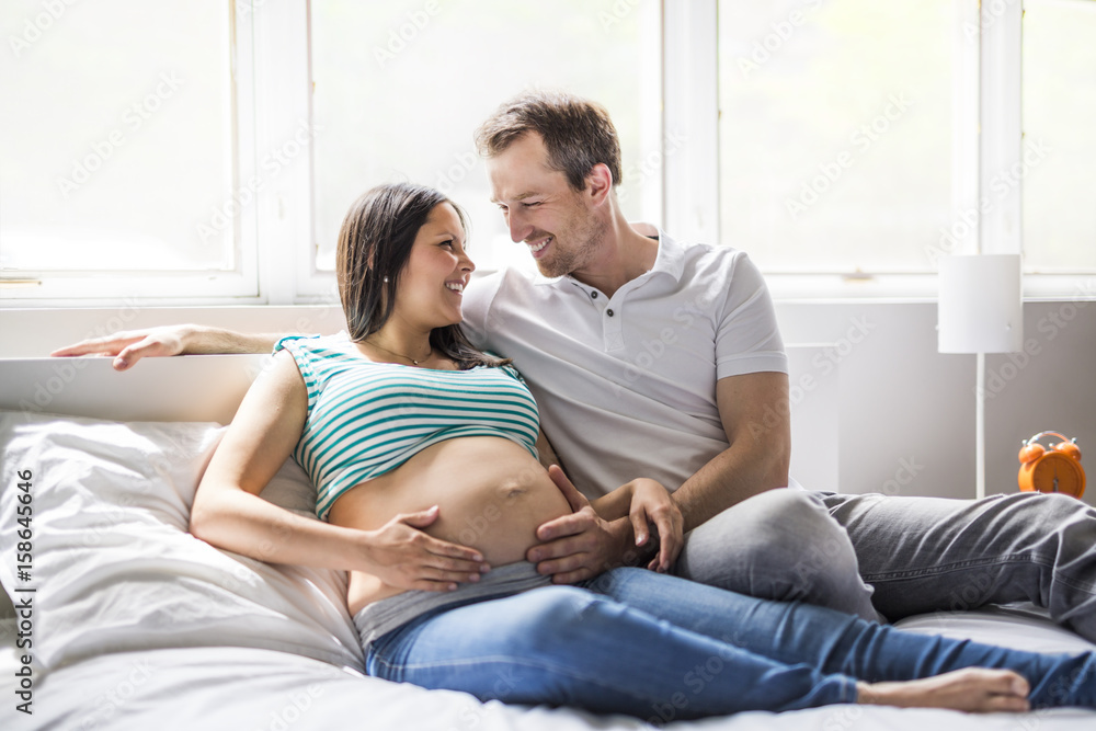 Young parents in bed expecting a little baby, Romantic moments for pregnant couple