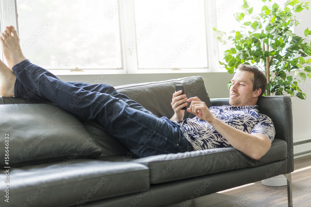 Obraz premium man using cell phone while laying on couch