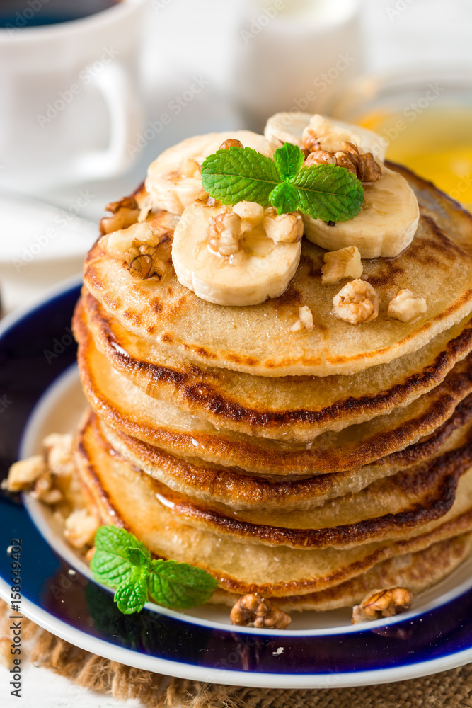 Pancakes with banana, honey, walnuts and mint on plate. Pancakes with banana, honey, walnuts and mint on plate.