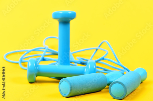 Shaping concept with blue dumbbells and skipping rope