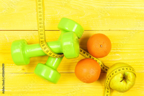 sport and health concept, dumbbells weight with measuring tape, fruit