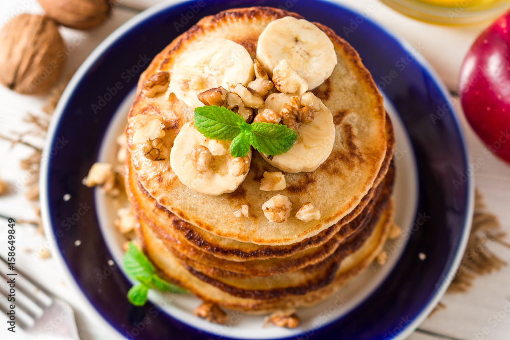 Pancakes with banana, honey, walnuts and mint on plate. Pancakes with banana, honey, walnuts and mint on plate.
